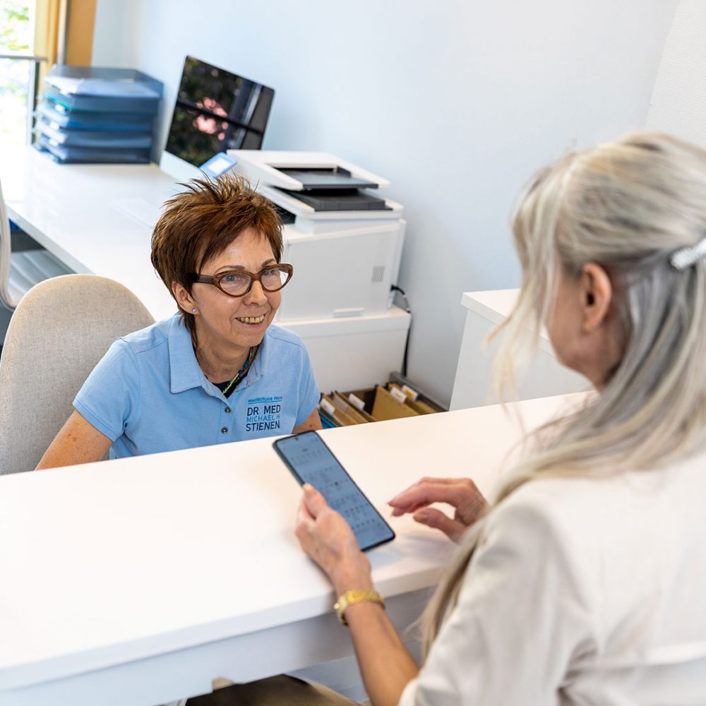 Medizinische Fachangestellte der neurologischen Privatpraxis Dr. Stienen in Karlsruhe berät eine Patientin am Empfang